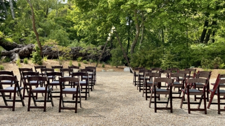 wooded ceremony site with chairs and triangle arch