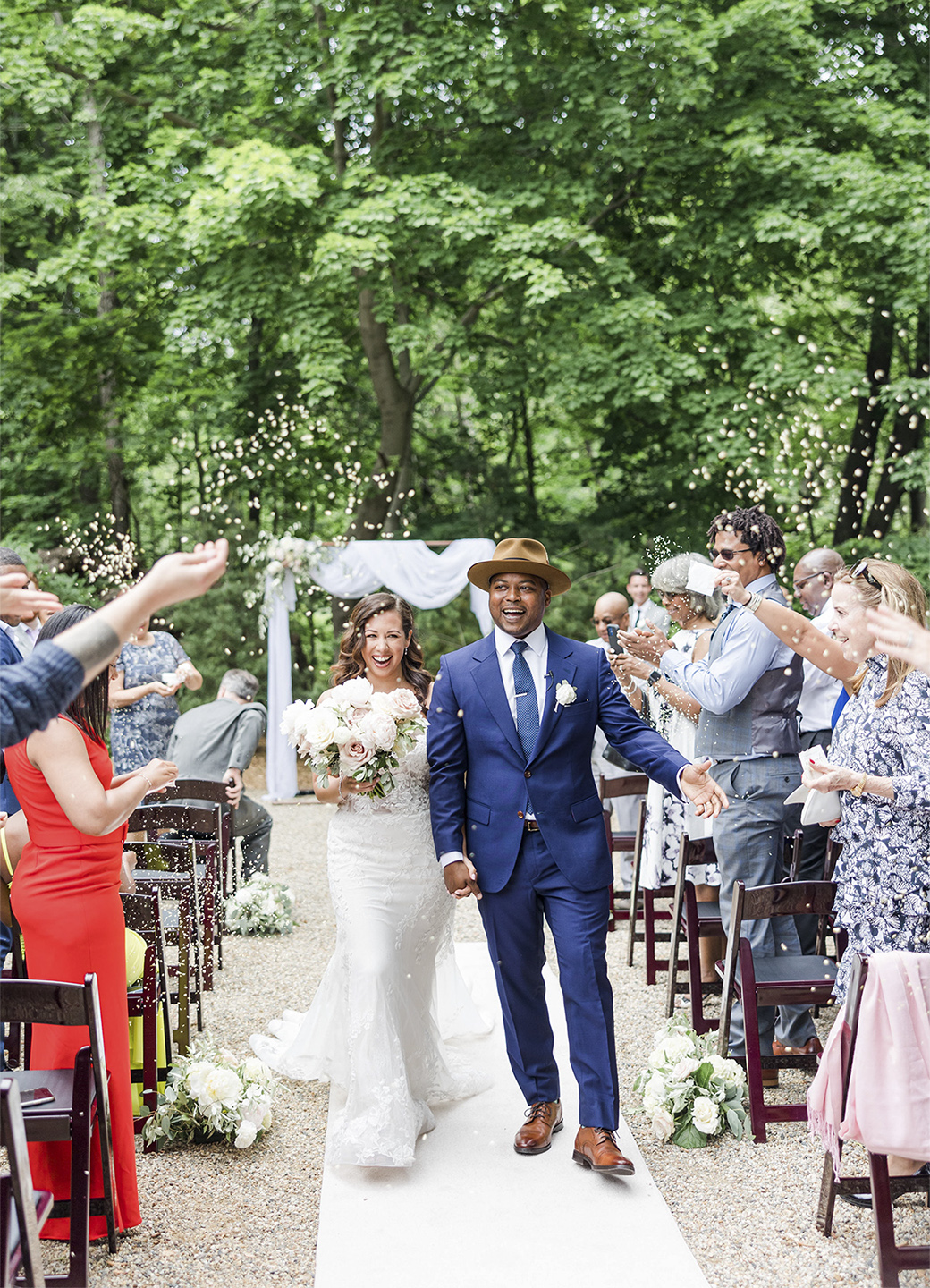 Married couple walking down the isle in outdoor wooded ceremony.