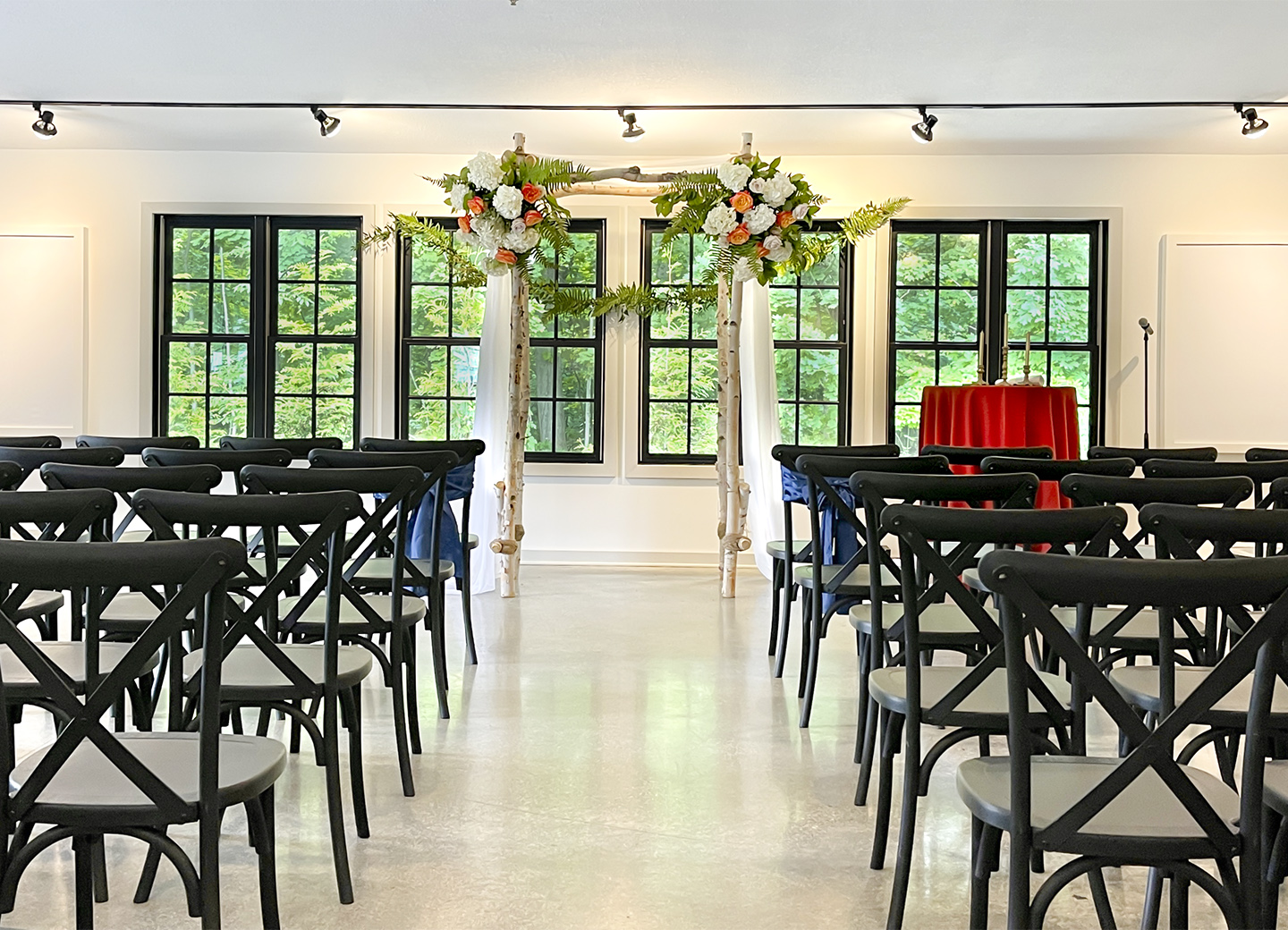 Ceremony set up indoor dining area with black cross back chairs and hoopo with flowers.