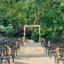 wooded ceremony site with pink draped arch
