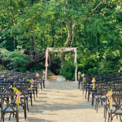 wooded ceremony site with pink draped arch